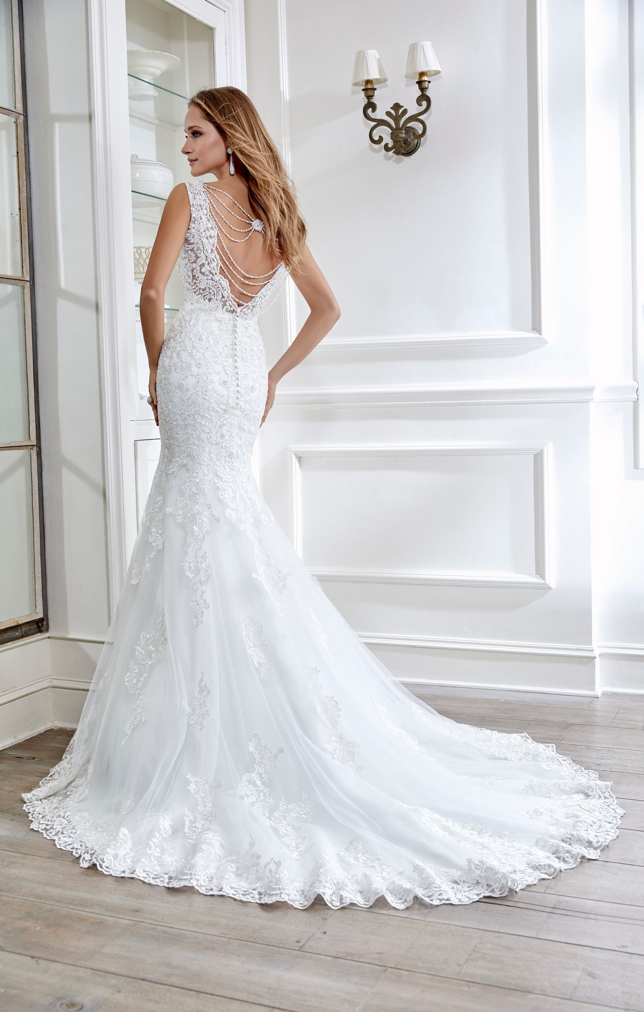 Woman standing in front of mirror wearing mermaid wedding dress with v-neckline and lace appliques
